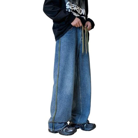 Person wearing blue jeans and black shoes standing on a wooden staircase.