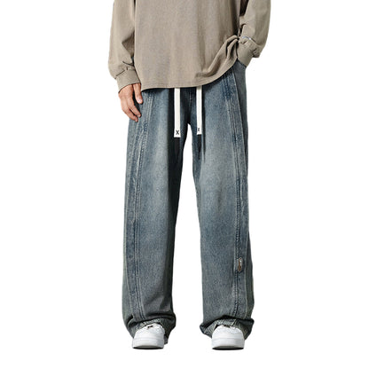 Person wearing a beige sweater and blue jeans on a dark background