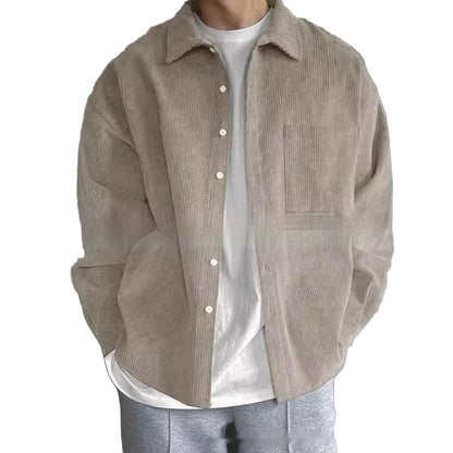 Person wearing a beige corduroy shirt over a white shirt with a plain background