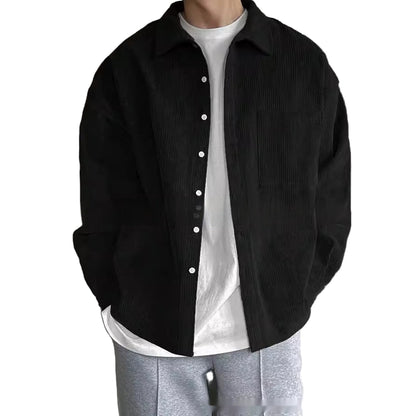 Person wearing a black jacket over a white shirt with a neutral background