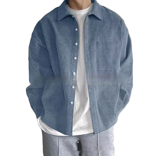 Person wearing a blue corduroy shirt over a white shirt with a neutral background